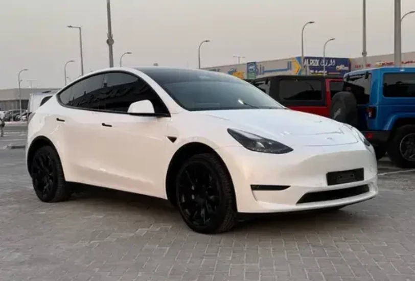 a tesla model y car parked on a brick surface